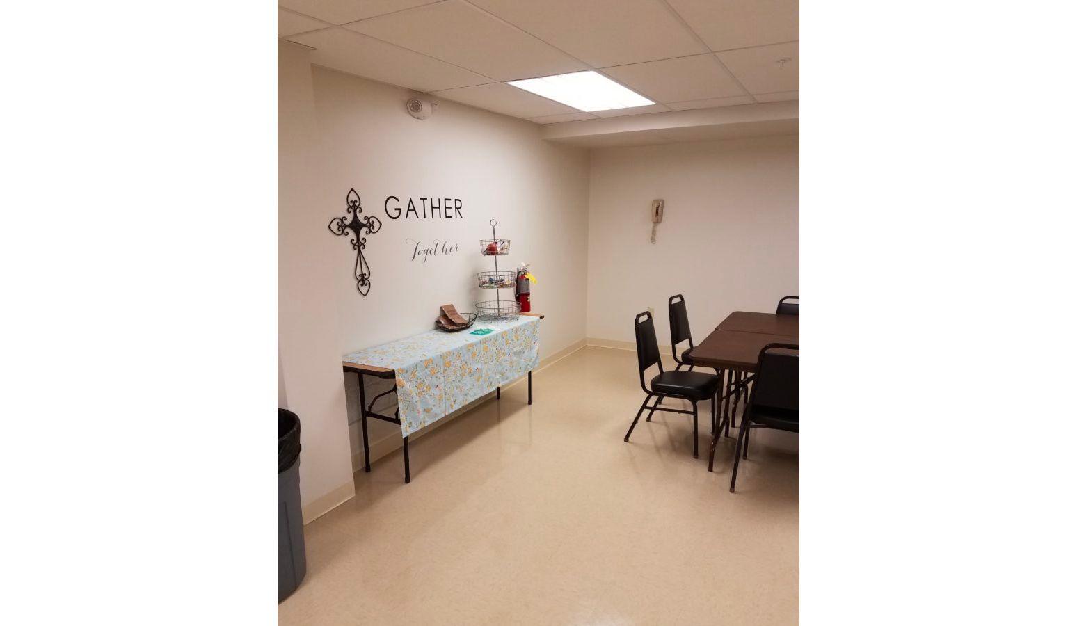 Breakroom with a few tables, chairs, and text on the wall.