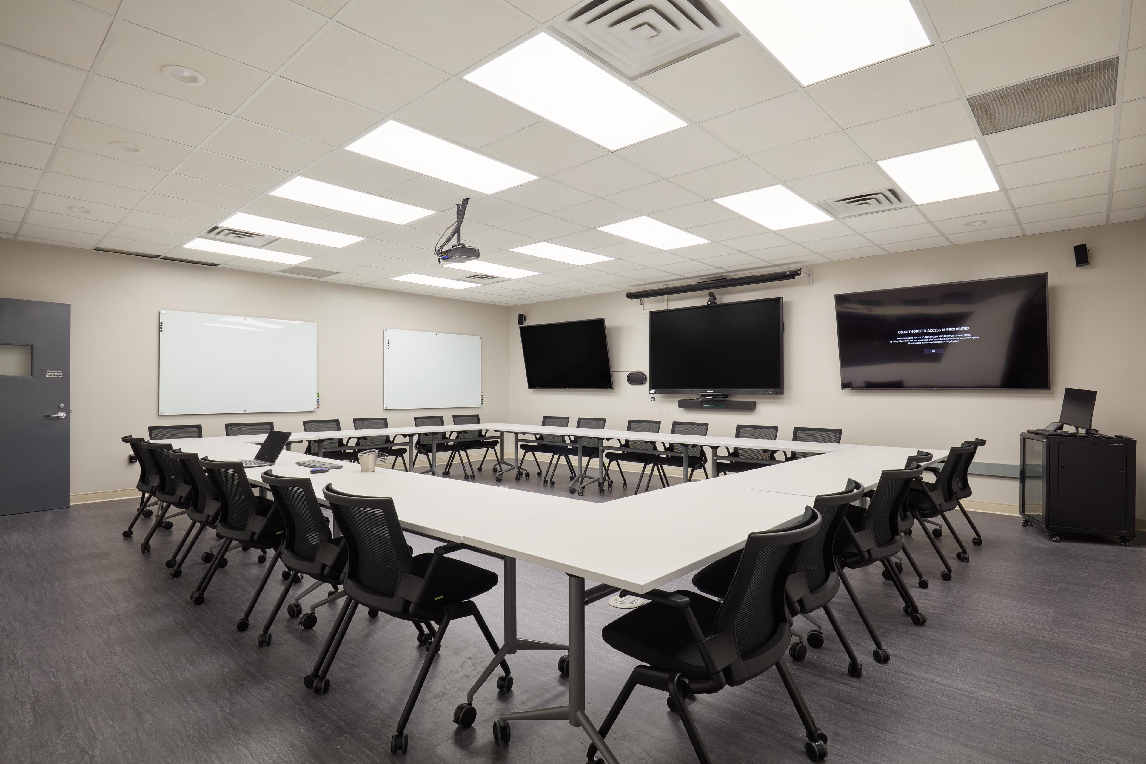 meeting room with tables, chairs, and screesn